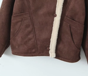 Détail de l'ourlet d'une veste en daim marron avec doublure en fausse fourrure beige et poche