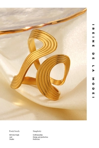 Macro shot of gold twisted ring with ripple texture on beige silk fabric backdrop