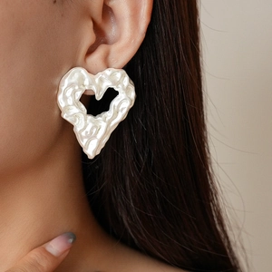 Orecchini a cuore irregolari con texture argento metallizzato su modella donna