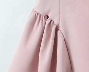 Close-up of pink ruched dress detail showing pleated fabric texture and stitching