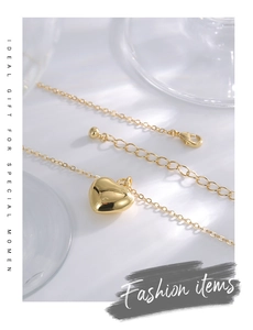 Close-up of gold heart necklace clasp with adjustable chain and round metal ball detail