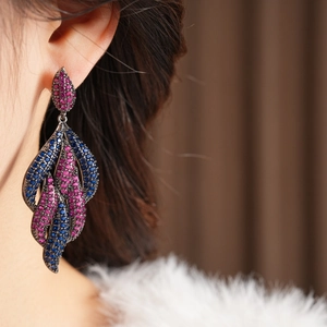 Close-up of vintage long drop earrings with pink and blue zircon stones on a model