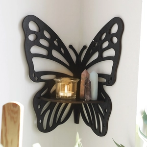 Macro detail of black butterfly cutout corner shelf holding candles and crystals