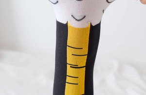 Close-up detail of knitted chicken claw pattern socks with yellow stripes and elastic texture