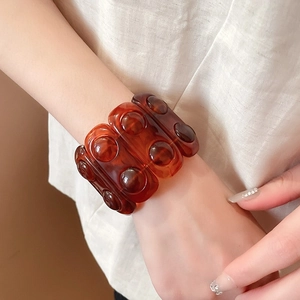 Detail of amber resin wide bangle with rounded relief texture on female wrist