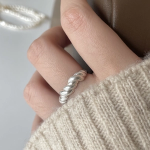 Detail of twisted 925 sterling silver rope ring worn against a knit sleeve