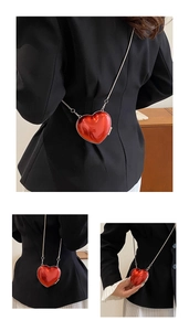 Macro detail of glossy red heart-shaped mini bag with fine silver metal chain strap