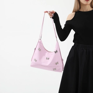 Pink shoulder bag with silver butterfly accessories shown by a model on white background