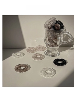 Detailed physical display of elastic spiral hair ties in clear, brown, and black colors