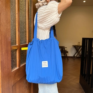 Close-up of blue pleated tote bag with Sozakka label on a shoulder-worn model