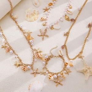 Detail of golden beach jewelry set with pearls, shells, and starfish on sand