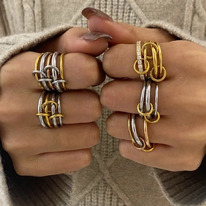 Close-up of stacked stainless steel rings in gold, silver, and rose gold finishes with crystals