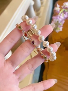 Detailed close-up of a pearl bracelet and colorful teardrop zircon bangle for women