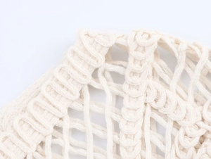 Detailed macro view of the cream crochet knit fabric with hollow mesh patterns