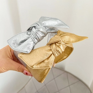 Close-up of gold and silver metallic faux leather bow headbands with pleated texture