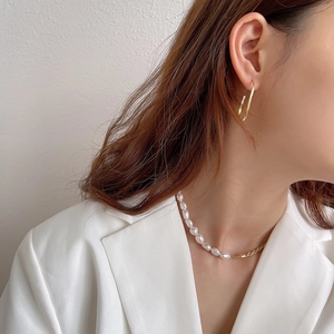 Close-up of elegant baroque pearl necklace and minimalist gold geometric earrings