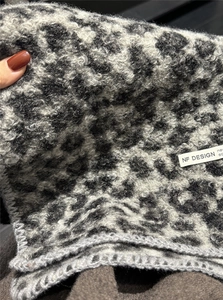 Detailed close-up of leopard print wool blend scarf with branded fabric label and soft texture