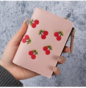 Detail of pink embroidered cherry pattern on short faux leather wallet with zipper