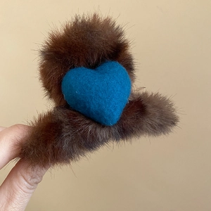 Gros plan sur la pince à cheveux en peluche marron avec un détail de cœur bleu doux
