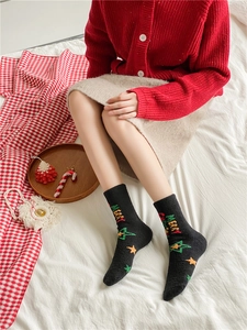 Détail de chaussettes de Noël en polaire corail avec broderie Merry Christmas sur tricot noir