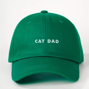 Detailed close-up of CAT DAD white embroidery on green twill cotton baseball cap