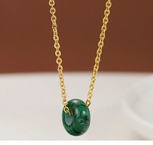 Macro detail of round green malachite pendant on a thin gold-plated O-chain necklace