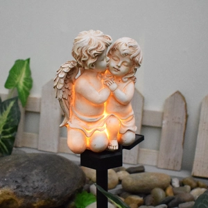 Solar outdoor garden light with glowing resin angel statues on a black ground stake