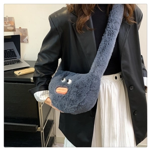 Detail of grey plush crossbody bag featuring big white eyes and pink sausage lips on a model