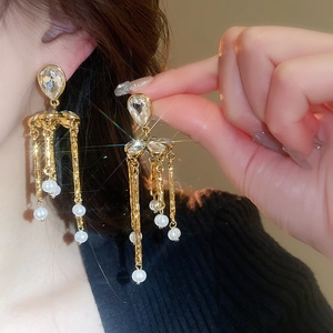 Gros plan de boucles d'oreilles dorées à pampilles avec cristal et perles élégantes