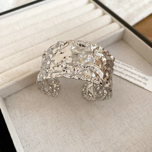 Detail of silver-tone wide cuff bracelet with crumpled liquid metal texture in velvet box