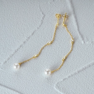 Macro shot of S925 silver gold-plated long chain earrings with tassels and white pearls