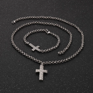 Close-up of vintage steel cross jewelry set with necklace and bracelet on black textured background
