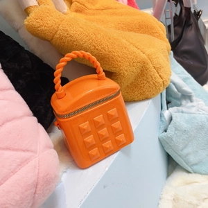 Close-up of orange jelly bucket bag with studs and twisted handle detail