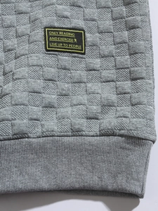 Close-up of light grey waffle knit fabric with unique textured pattern and chest patch