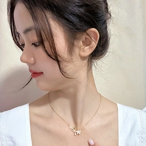 Close-up of rose gold floral pendant necklace with green leaf detail on a model