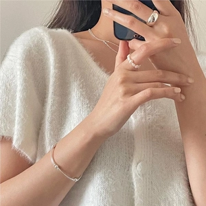 Detail shot of a silver beaded elastic bracelet and minimalist ring on a model
