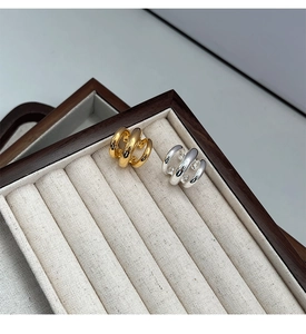 Close-up of gold and silver multi-layer C-shaped ear cuffs on a jewelry tray