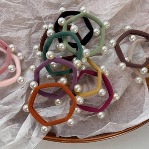 Elastic ponytail hair ties set with pearls in assorted colors on a wooden tray
