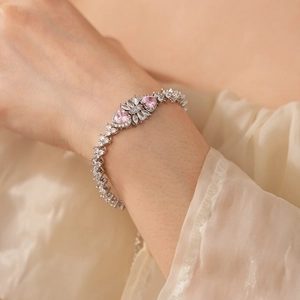 Detail of silver bracelet with pink heart-shaped stones and floral zircon accents