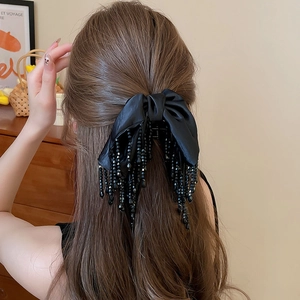Vue détaillée d'une pince à cheveux vintage avec nœud en satin noir et pompons
