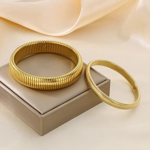 Macro shot of gold Tubogas style elastic steel bracelets on luxury champagne satin fabric