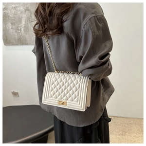 Close-up of white quilted crossbody bag with metal chain strap and flap closure