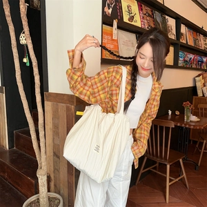 Detail view of white pleated tote bag texture and Sozanya label in a retro cafe setting