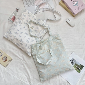 Detail showing high-capacity canvas tote bag with cute cat prints and interior woven label