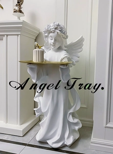 Detail of angel figurine holding a gold metal tray with decorative candle holder