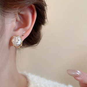 Elegant baroque pearl stud earring with gold geometric metal frame on female model