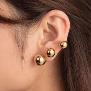 Three sizes of polished gold stainless steel ball stud earrings worn in a stacked style