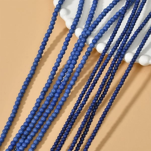 Macro detail of 3/4mm blue turquoise loose round beads on a white ceramic plate