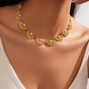 Détail d'un collier doré en éventail avec cristaux porté sur le cou d'une femme