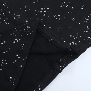 Gros plan détaillé des coutures de l'ourlet et des paillettes argentées sur tissu noir